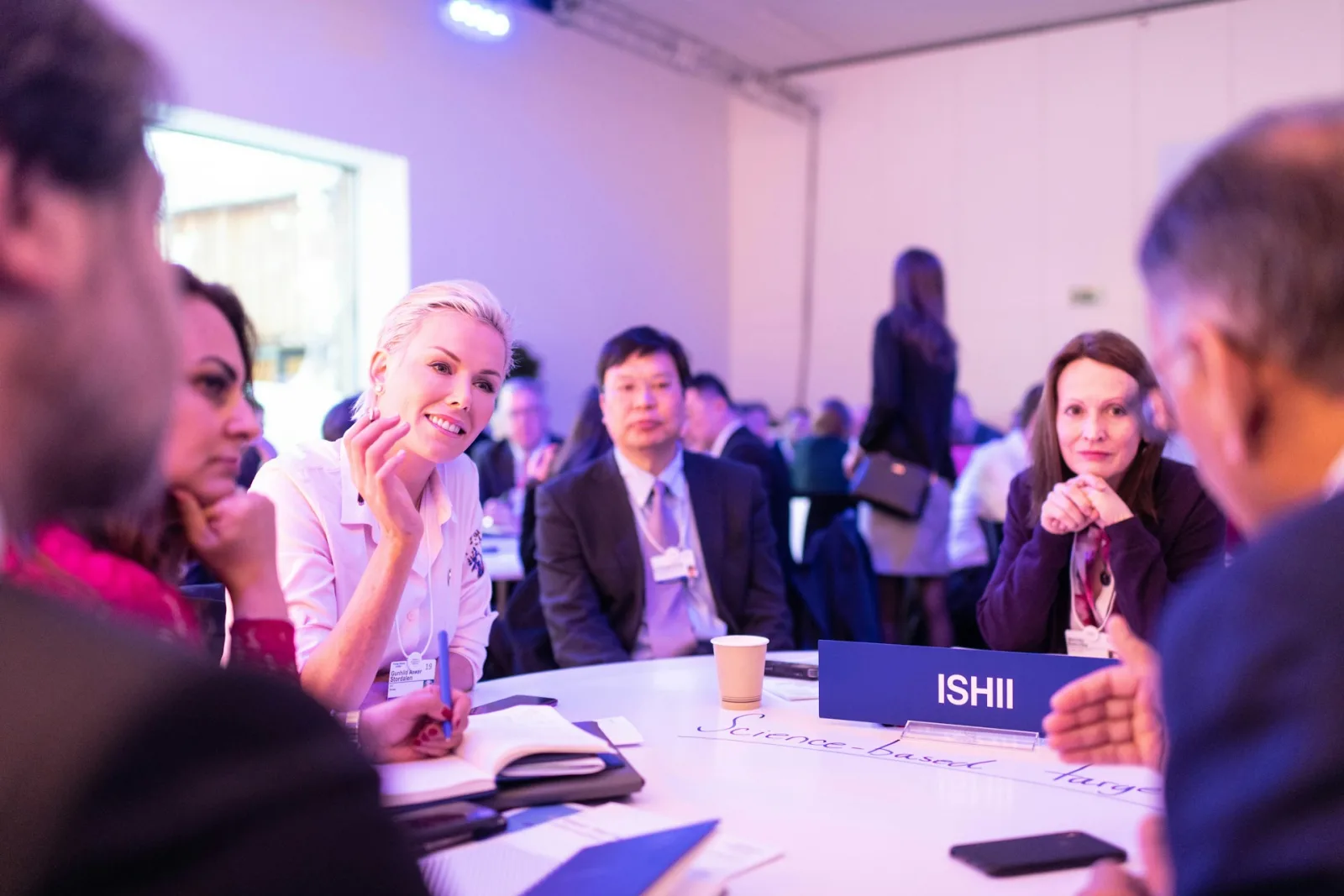 Delegates wearing conference badges in discussion around a table at a conference